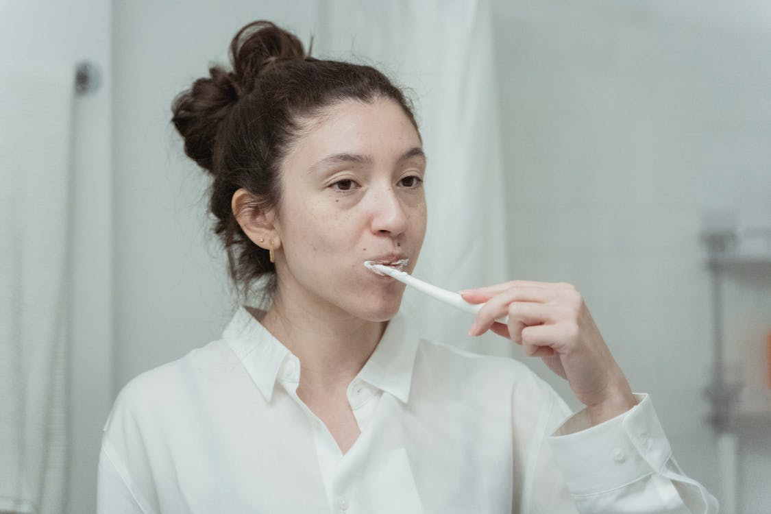 a woman brushing her teeth in-front of a mirror