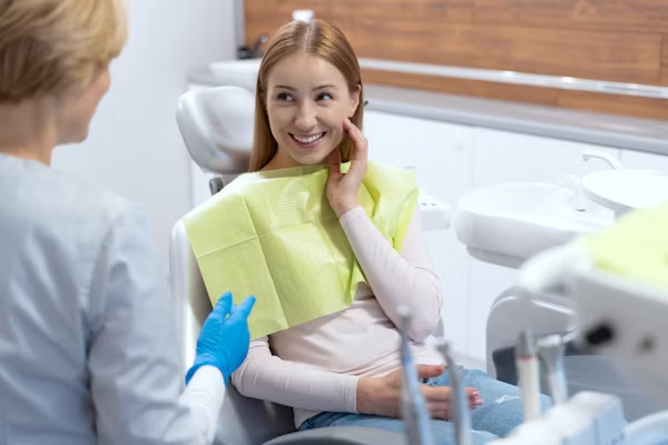 a woman sitting on the dental chair while smiling at the dentist